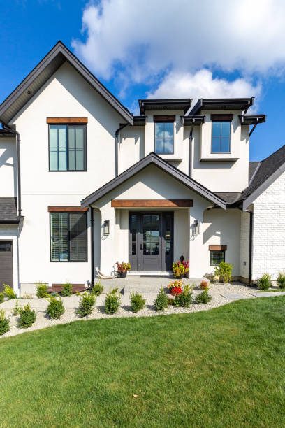 Front view of luxury two garage home with luscious green grass  on a blue sky day.